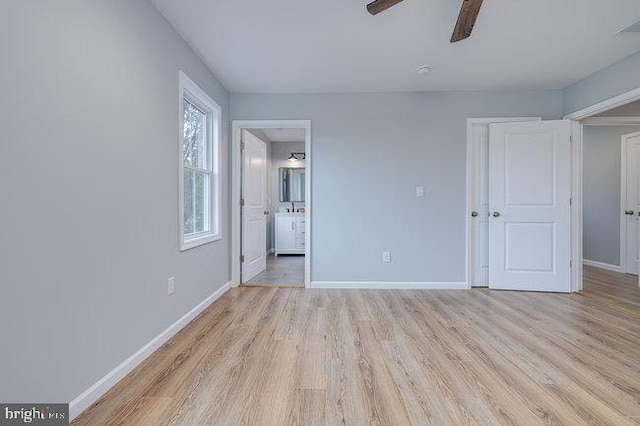 unfurnished bedroom featuring light wood-type flooring, ensuite bath, and ceiling fan