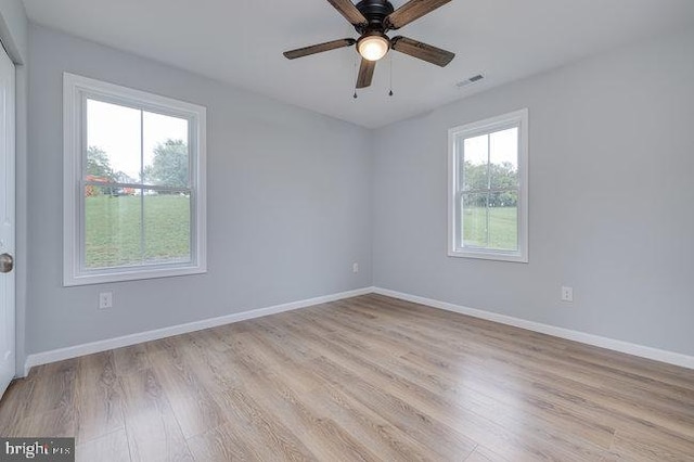 spare room with light wood-type flooring, ceiling fan, and plenty of natural light