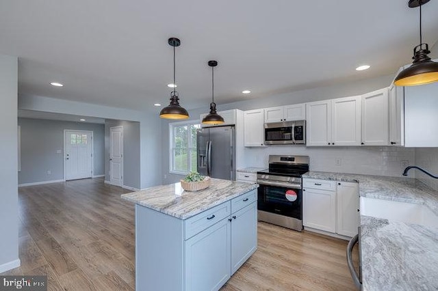 kitchen featuring pendant lighting, light hardwood / wood-style flooring, white cabinetry, stainless steel appliances, and a center island