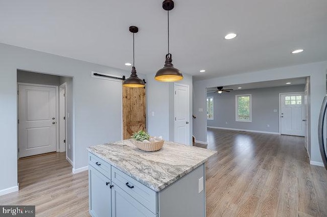 kitchen featuring light hardwood / wood-style flooring, ceiling fan, hanging light fixtures, and a barn door