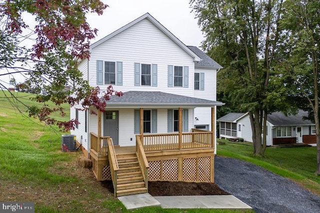 view of front of house featuring central AC, a front yard, and covered porch