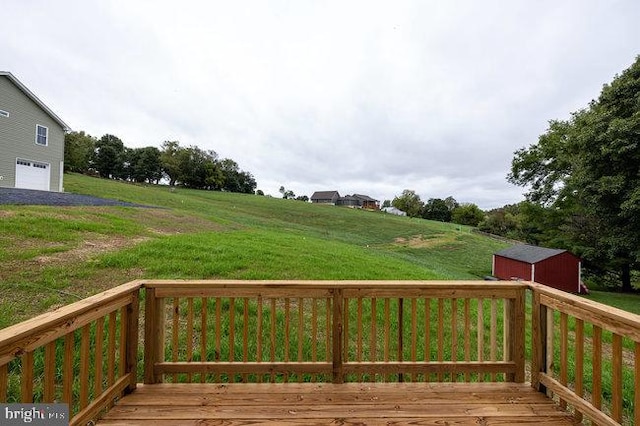 wooden deck featuring a garage, a yard, and a storage unit