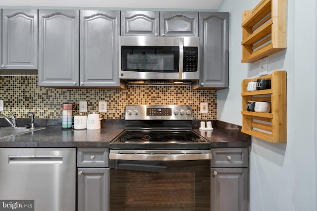 kitchen with gray cabinets, stainless steel appliances, and decorative backsplash