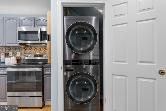 washroom with stacked washer and clothes dryer and light wood-type flooring