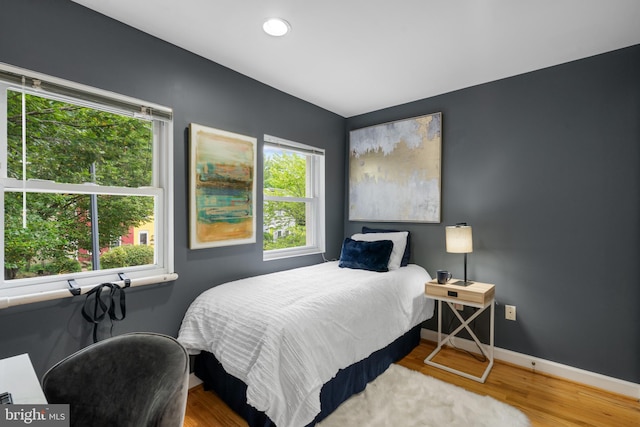 bedroom with multiple windows and hardwood / wood-style floors