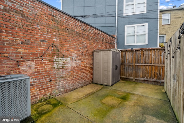 view of patio with central AC and a shed