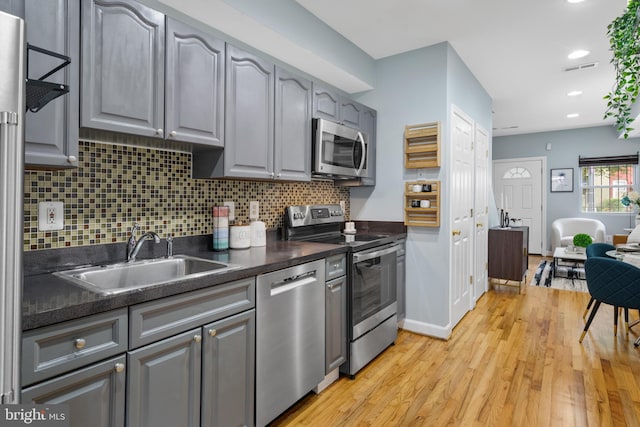 kitchen featuring light hardwood / wood-style floors, gray cabinets, stainless steel appliances, and sink