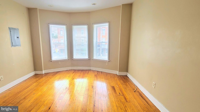 unfurnished room with electric panel and light hardwood / wood-style flooring