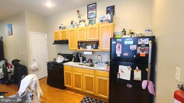 kitchen featuring light brown cabinets, sink, light hardwood / wood-style flooring, and black appliances