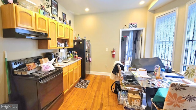 kitchen featuring sink, light brown cabinetry, black appliances, and light hardwood / wood-style floors