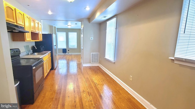 kitchen featuring light brown cabinets, light wood-type flooring, black range with electric stovetop, and sink