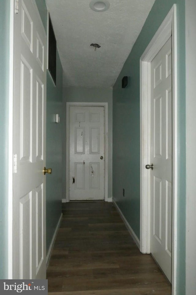 hall featuring a textured ceiling and dark hardwood / wood-style floors