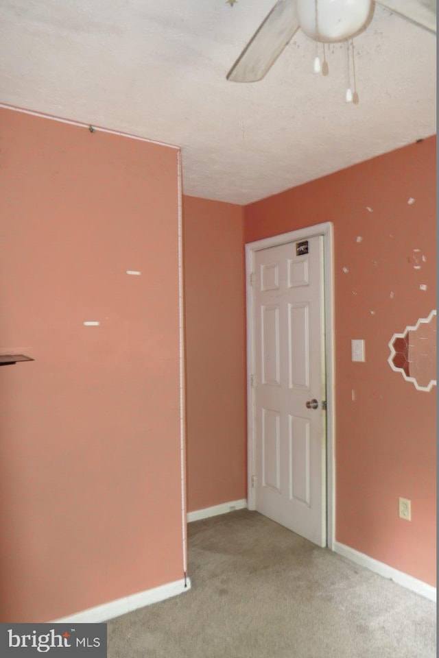 carpeted spare room with a textured ceiling and ceiling fan