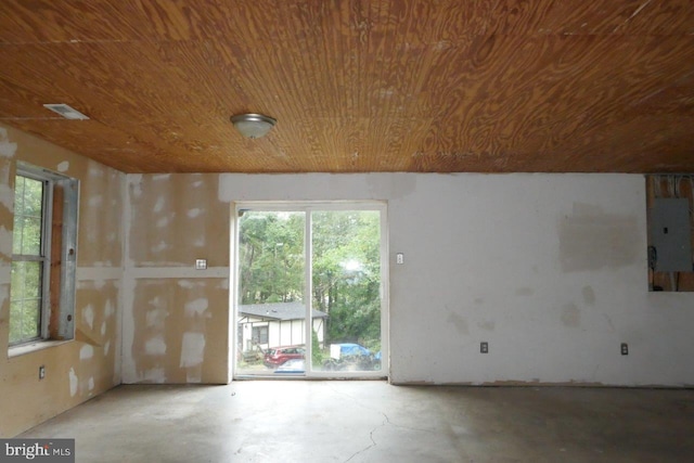 empty room with wooden ceiling, concrete flooring, and electric panel