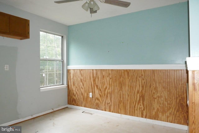 empty room with wood walls and ceiling fan