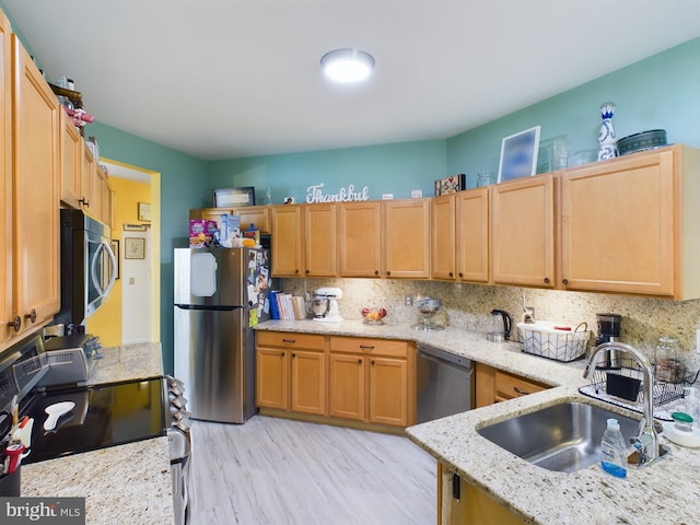 kitchen featuring light hardwood / wood-style floors, sink, backsplash, appliances with stainless steel finishes, and light stone countertops