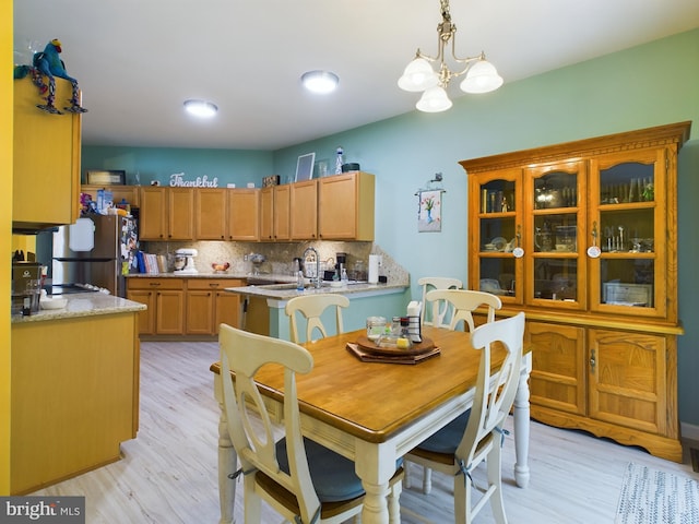 dining space featuring an inviting chandelier, light hardwood / wood-style floors, and sink