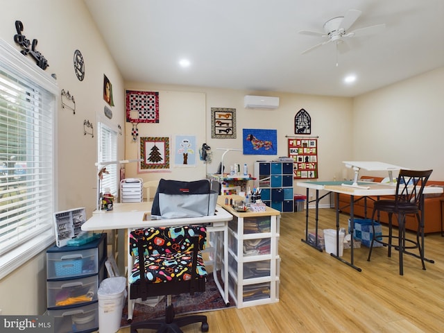 office space with light wood-type flooring, ceiling fan, and a wall mounted air conditioner