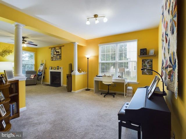 carpeted office with decorative columns, ceiling fan, and a wealth of natural light