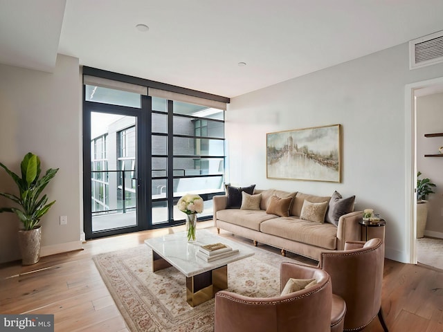 living room with a wall of windows and light hardwood / wood-style flooring