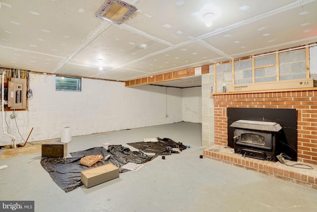 basement with electric panel, a fireplace, and a wood stove