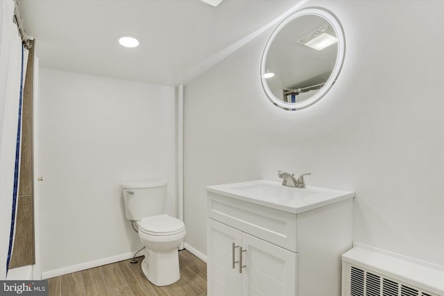 bathroom with vanity, radiator, hardwood / wood-style floors, and toilet