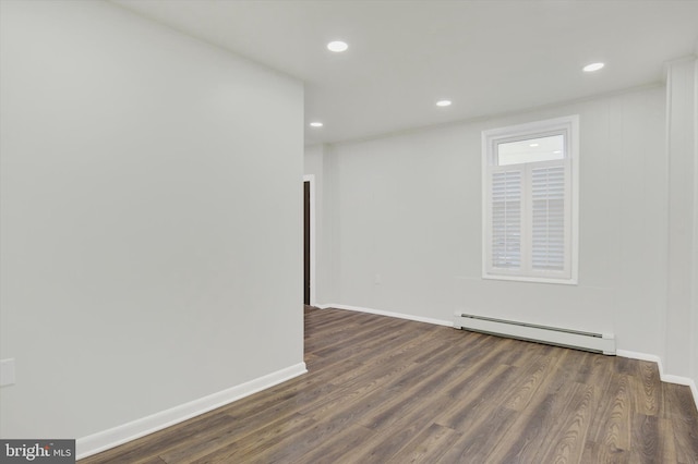 spare room featuring dark hardwood / wood-style flooring and a baseboard heating unit