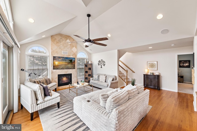 living room with lofted ceiling, a large fireplace, ceiling fan, and light hardwood / wood-style flooring