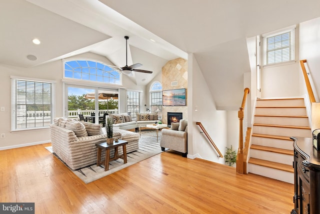 living room with light hardwood / wood-style floors, vaulted ceiling, ceiling fan, and a premium fireplace