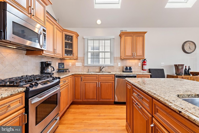 kitchen with decorative backsplash, stainless steel appliances, light hardwood / wood-style floors, and sink