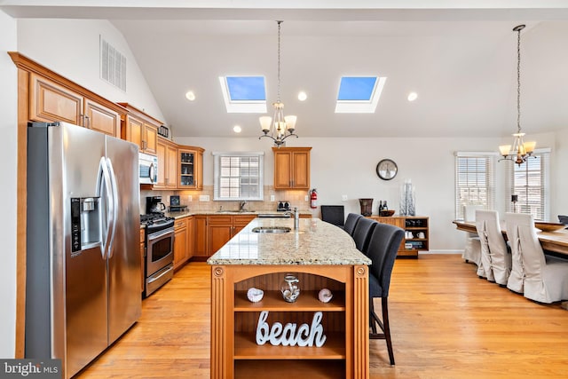 kitchen featuring a notable chandelier, stainless steel appliances, lofted ceiling with skylight, and a kitchen breakfast bar