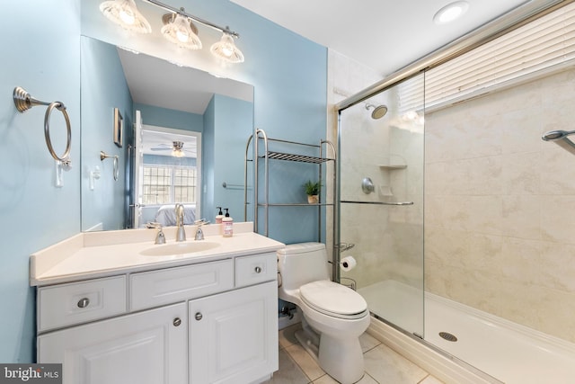 bathroom with a shower with door, tile patterned floors, ceiling fan, vanity, and toilet