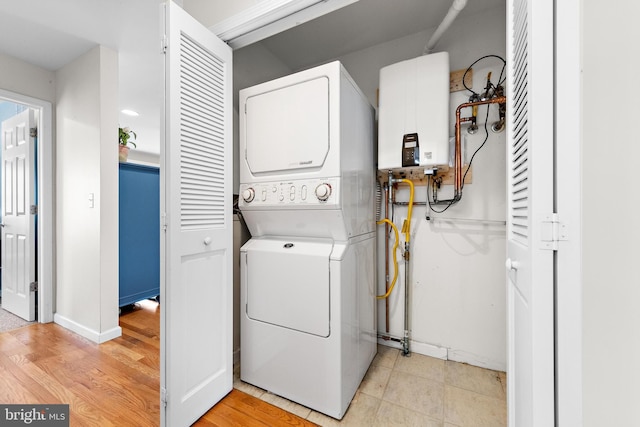 laundry room featuring water heater, stacked washer / dryer, and light hardwood / wood-style floors