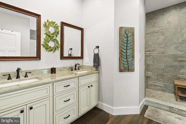 bathroom with vanity, a tile shower, and wood-type flooring