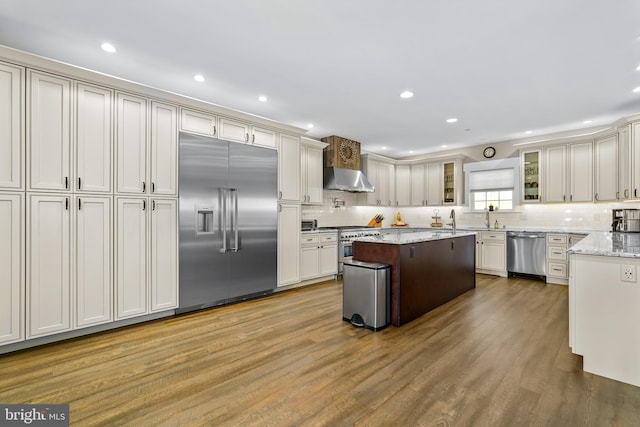 kitchen featuring hardwood / wood-style flooring, decorative backsplash, high end appliances, and light stone counters