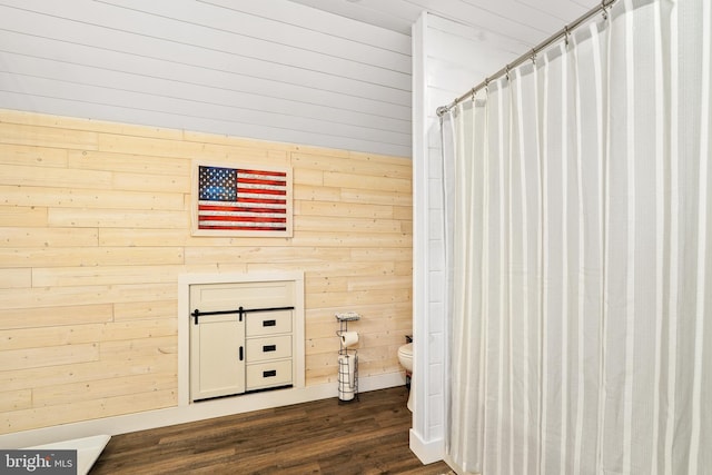 bathroom with wood walls, a shower with shower curtain, wood-type flooring, and toilet