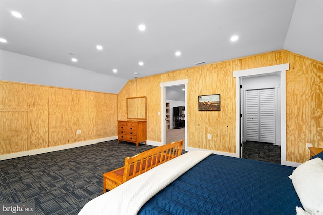 bedroom featuring wooden walls, lofted ceiling, and dark colored carpet