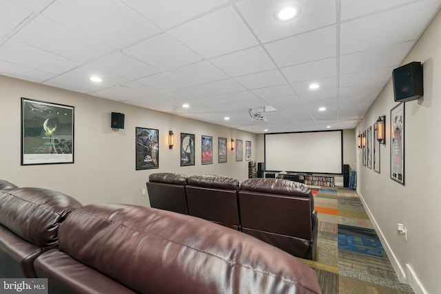 carpeted home theater room featuring a paneled ceiling