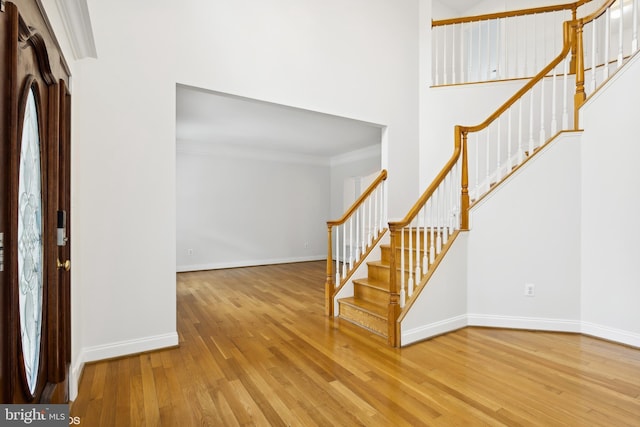 foyer entrance featuring ornamental molding, baseboards, stairs, and wood finished floors