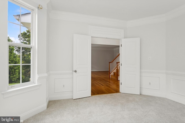 carpeted empty room featuring ornamental molding and plenty of natural light