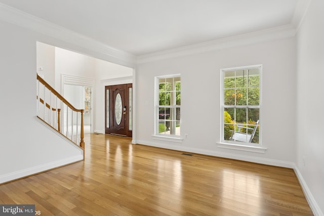 foyer with stairs, a wealth of natural light, light wood-style floors, and ornamental molding