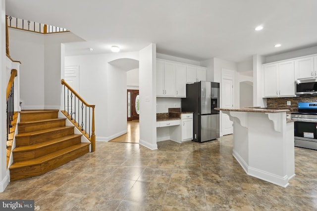 kitchen featuring appliances with stainless steel finishes, a breakfast bar, white cabinetry, and a center island