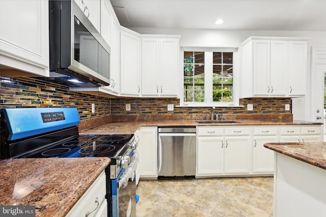 kitchen featuring appliances with stainless steel finishes, dark stone counters, white cabinetry, and sink