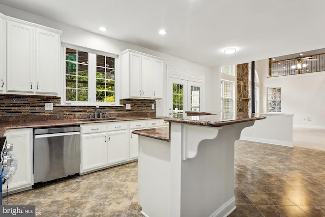 kitchen with tasteful backsplash, a breakfast bar, stainless steel dishwasher, a sink, and white cabinets