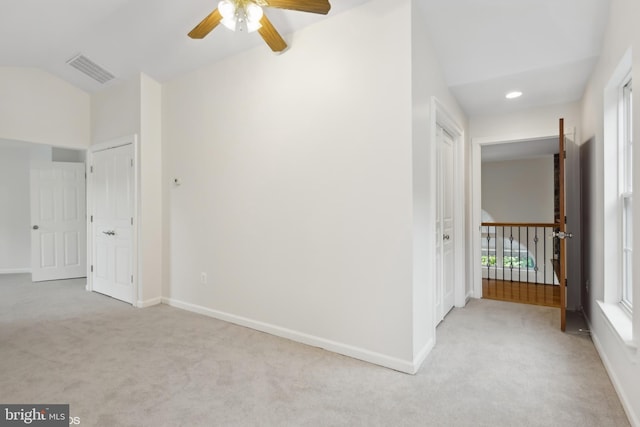 interior space featuring light colored carpet, visible vents, baseboards, and vaulted ceiling