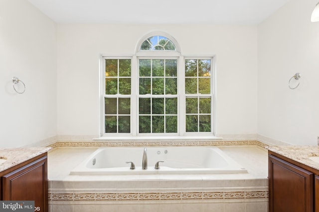 bathroom featuring a relaxing tiled tub and vanity