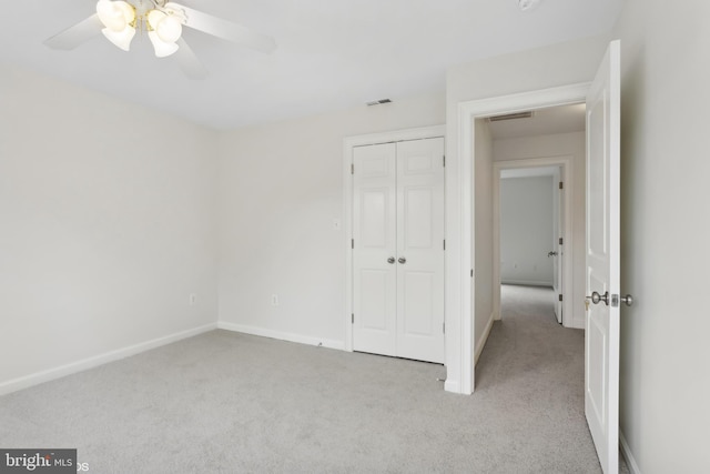 unfurnished bedroom featuring light carpet, a closet, and ceiling fan