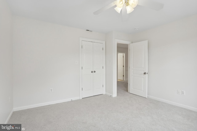 unfurnished bedroom featuring ceiling fan, light colored carpet, and a closet