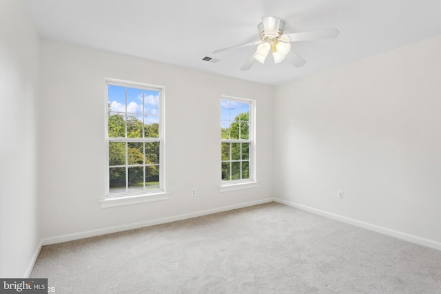 carpeted spare room featuring baseboards, visible vents, and a ceiling fan