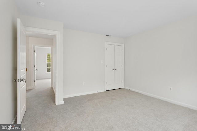 empty room featuring baseboards and light colored carpet